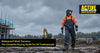 Tradesperson wearing waterproof bib and brace overalls working in heavy rain on a UK construction site