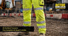 Worker wearing hi vis work trousers on a UK construction site with EN ISO 20471 reflective tape visible