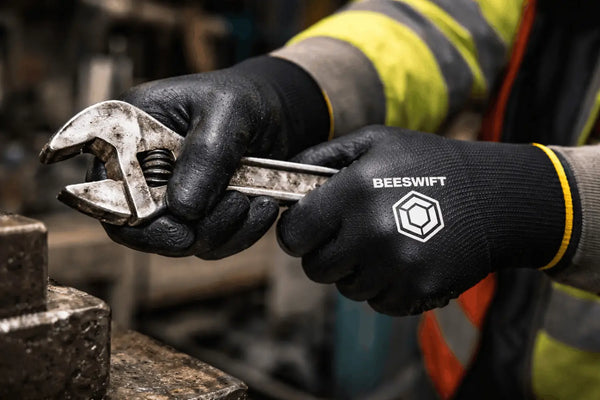 worker gripping metal tool with textured nitrile coated work gloves